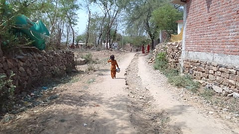 चरू (छोटे स्टील के घड़े में) पानी लेने जाती एक बच्ची।