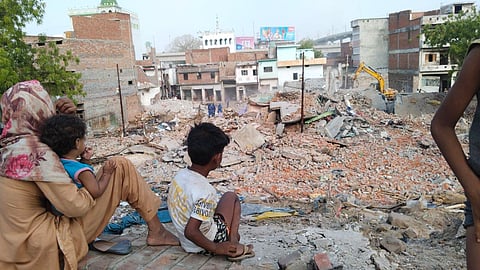 अकबरनगर में अपने टूटते मकान को देखती महिला.