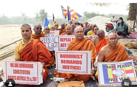 धूप में बैठे भिक्षु और उनके समर्थक अपने आमरण अनशन के 19वें दिन में हैं।