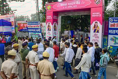 Police personnel stand guard amid the rush to ensure security at A.N. College during the Bihar Assembly election vote-counting in Patna on Friday, November 14