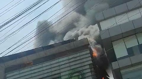 Thick black smoke emerging from the top floor of the building