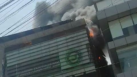 Thick black smoke emerging from the top floor of the building