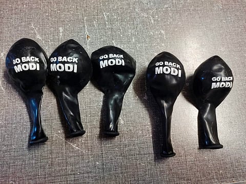 Black balloons printed with the slogan 'Go Back Modi'.