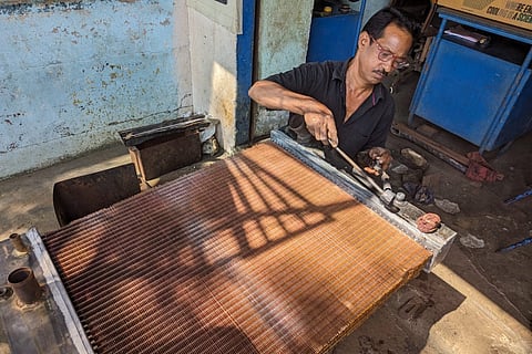 Azeez welds the edges of an oil cooler in Vijayawada's Autonagar.