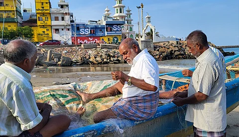 Mariasusai (middle) inspects fishing nets with his coworkers at the Vavathurai coast in Kanniyakumari