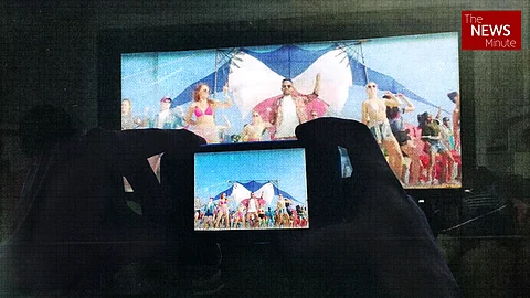 A person filming a movie in a cinema hall with a mobile phone