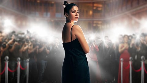 Image of actor Nayanthara, dressed in a black dress, looking back at the camera as paparazzi surround her to click pictures.