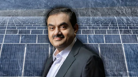 A professional portrait of Gautam Adani is superimposed on a background of solar panels, symbolizing his involvement in the solar energy sector. The image uses a blue-toned aesthetic to emphasize a focus on clean energy and corporate prominence.