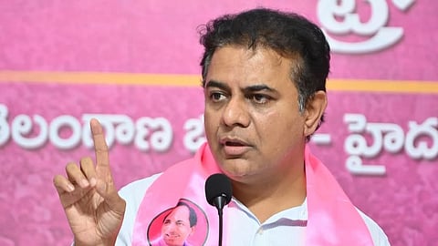 BRS leader KTR in a whire shirt wearing a pink scarf with a stern expression and a finger raised.