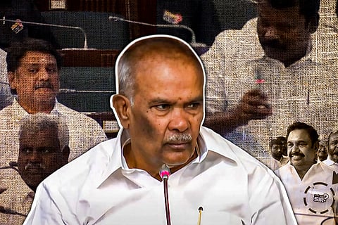 Tamil Nadu Assembly Speaker Appavu and former Chief Minister Edappadi K. Palaniswami are seen in white attire during a protest in the Assembly. Edappadi and his AIADMK party members are demonstrating against the Anna University sexual assault case, wearing badges that read "Who is that sir?" They are being denied screentime on the official broadcast of the Assembly proceedings, highlighting their dissent regarding the handling of the case