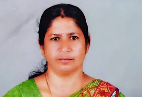 Portrait of Radha wearing a green and red saree, looking directly at the camera.