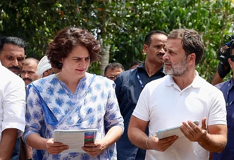 Rahul Gandhi and Priyanka Gandhi engaging in conversation, set against a neutral background.