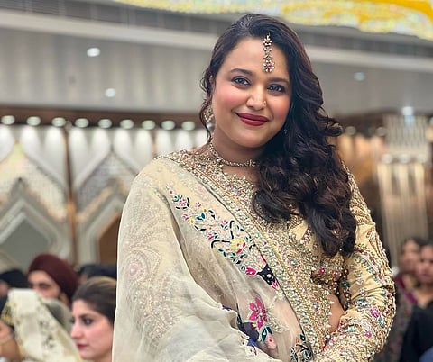 The actor Swara Bhaskar in a white lengha with heavy embroidery, smiling and wearing jewellery