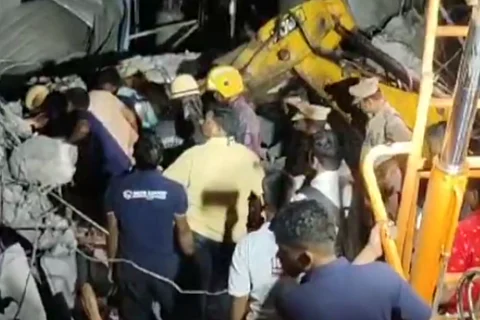 Group of men surrounded by rubble. A JCB deployed to excavate the rubble.