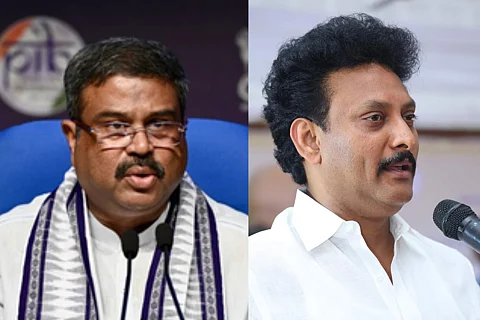 (R) Union Minister for Education Dharmendra Pradhan; (L) Tamil Nadu Minister for School Education Anbil Mahesh Poyyamozhi. Dharmendra is in a white kurta with a black and white scarf, seated on a blue chair. Anbil is wearing a white shirt and speaking at mic.