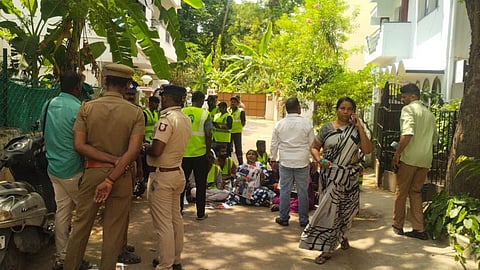 Police standing to the left, facing sanitary workers wearing neon green reflective jackets.