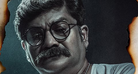 Rangayana Raghu as the introspective inspector in the Kannada film Agnyathavasi, wearing glasses and a serious expression, framed against a burnt-edged dark background.