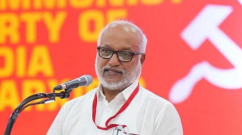 MA Baby, a senior leader of the Communist Party of India (Marxist), speaking at a podium with a red backdrop featuring the party's emblem and name.