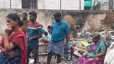 Affected people stand in the ruble of the razed houses.