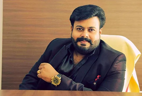 Image features Mukesh M Nair wearing black dress