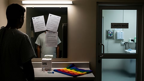 A person in a hospital gown stands in front of a mirror with rejection notices taped to it, including one that says "REJECTED" over an application form. On the counter below are hormone injection supplies and a folded rainbow flag. To the right, a door labeled "Surgery Ward" leads to a clinical room. The scene conveys emotional and systemic challenges faced by transgender individuals in accessing medical care.