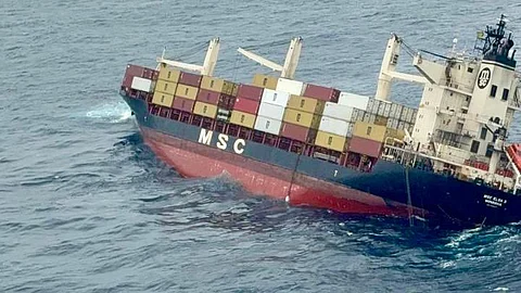 The image shows the container vessel, tilted to the right, in the sea.