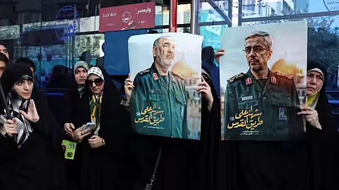 Iranians hold posters of late Islamic Revolutionary Guard Corps head Hossein Salami (left), and late Iranian Armed Forces Chief of Staff General Mohammad Bagheri (right), who were killed in Israeli airstrikes in recent days.