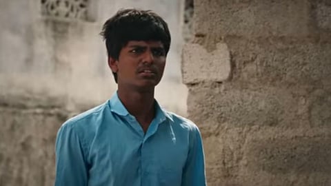 Screengrab of Mounesh Natranga from Hebbuli Cut, facing the camera, wearing blue colour school uniform shirt.