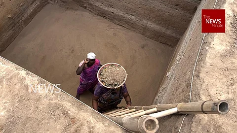 Image featuring two workers at the Keeladi excavation site, climbing up a trench using a ladder