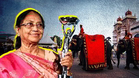 A woman in a pink sari holding a trophy. In the background is a man riding an elephant in front of the Mysore Palace.