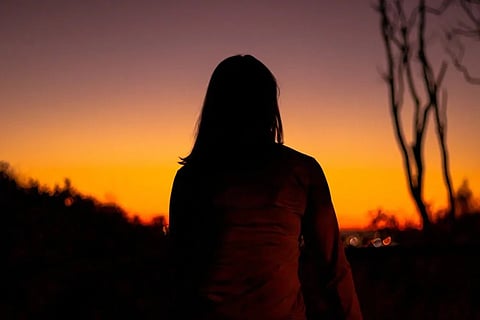 A representative silhouette of a woman against an orange sky