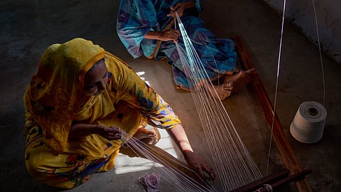 A top shot of two women artisans in sarees weaving the GI-tagged Pattamadai pai (mat) in TN's Tirunelveli district