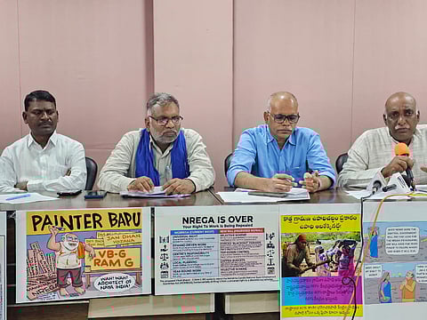 Four men sit at a press conference table lined with posters protesting changes to the MGNREGA employment scheme. The posters, featuring satirical cartoons and comparison charts, claim that the proposed "VB-GRAM G" bill will repeal the universal right to work in favor of a restrictive, "selective scheme."
