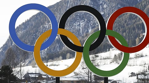People walk by the Olympic rings near the village of Anterselva, where the biathlon will take place during the Milan-Cortina 2026 Winter Olympics.