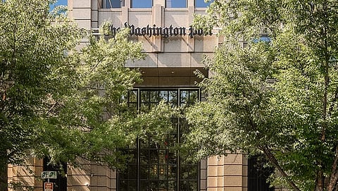 Image of a building, the headquarters of The Washington Post, partly covered by trees