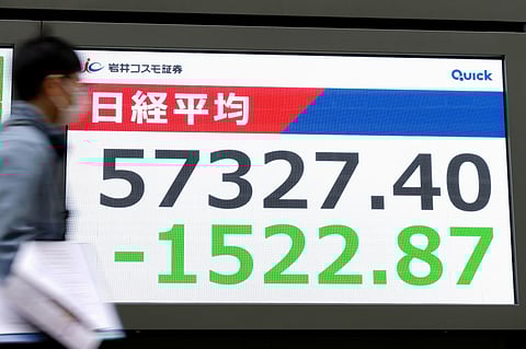 People walk in front of an electronic stock board showing Japan's Nikkei index at a securities firm Monday, March 1, 2026, in Tokyo.