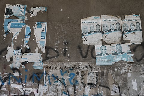 Old campaign posters from the 2016 presidential election cover a wall along a sidewalk in Port-au-Prince, Haiti, Monday, March 2, 2026.