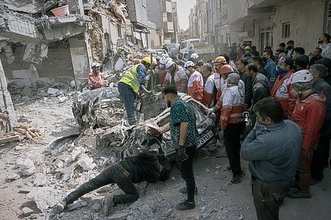 Firefighters look on as volunteers and first responders inspect the rubble and search for victims at a residential building hit in an overnight strike during the U.S.-Israeli military campaign in Tabriz, East Azerbaijan Province, northwestern Iran, Tuesday, March 24, 2026. (AP Photo/Matin Hashemi)