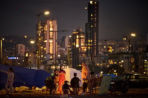 A family who fled Israeli shelling in southern Lebanon warm themselves by a bonfire next to tents used as shelters in Beirut, Lebanon, Tuesday, March 31, 2026.