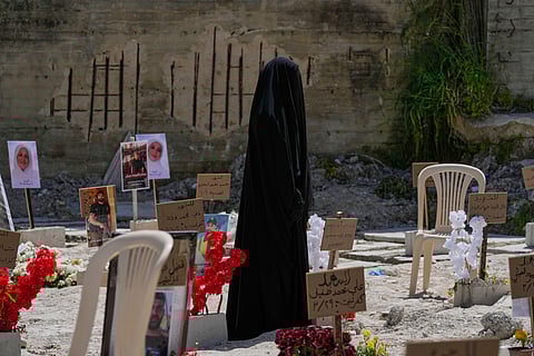 A veiled woman walks through a mass grave where civilians and Hezbollah fighters killed by Israeli airstrikes are temporarily buried in the southern port city of Sidon, Lebanon, Tuesday, April 14, 2026. (AP Photo/Mohammed Zaatari)