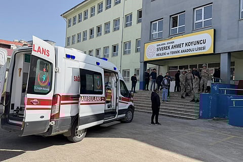 Turkish security forces and emergency staff stand at the courtyard of a high school where an assailant opened fire, in Siverek, south east Turkey, Tuesday, April 14, 2026,