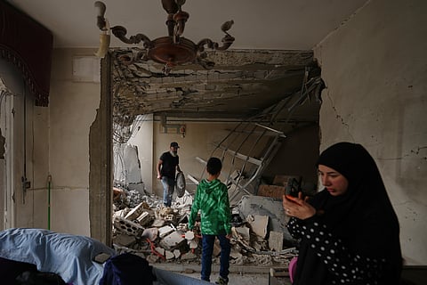 Fadi Al Zein, left, who lost both his homes in Israeli strikes in his village of Khiam and in Dahiyeh, searches through the rubble of his heavily damaged home as a child stands nearby, in Beirut's southern suburbs, Lebanon, Saturday, April 25, 2026.