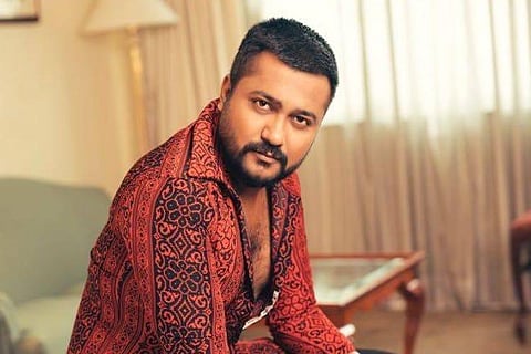 Actor Bobby Simha dressed in a red printed shirt and is seen striking a pose.
