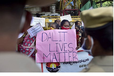 A woman holding up a poster which reads 'Dalit Lives Matter'