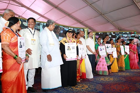 Rahul Gandhi, Mallikarjun Kharge Siddaramaiah and DK Shivakumar posing with Gruha Lakshmi beneficiaries