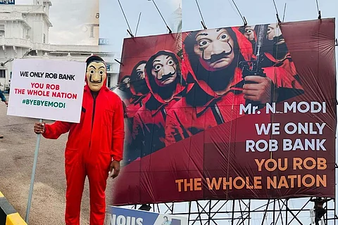 A "money heist" parody hoarding and a man with a suit with anti Modi writing.