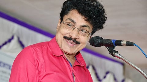 Image of PK Sasi on stage, speaking through a microphone