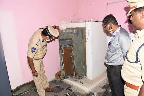 A bank official looks on as police inspect the crime scene at bank.