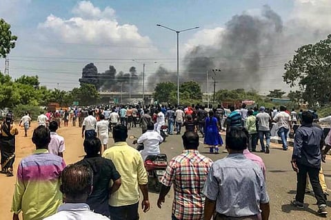 Anti-sterlite protesters watch as smoke engulfs the air in the distance during the 2018 protests
