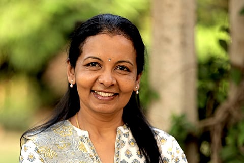 Valli Arunachalam looking into the camera and smiling wearing a white top